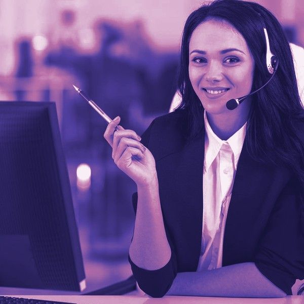 Atendente da Evenclick com headset, sorrindo, em frente ao computador